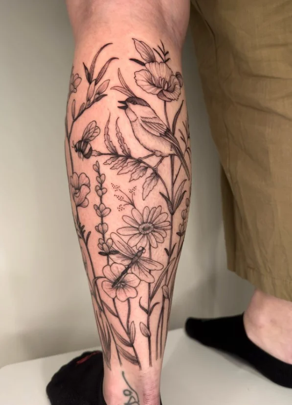 Wildflower lower leg tattoo arranged in a loose vertical bouquet