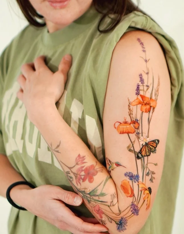 Wildflower upper arm tattoo with natural flowers and flowing stems