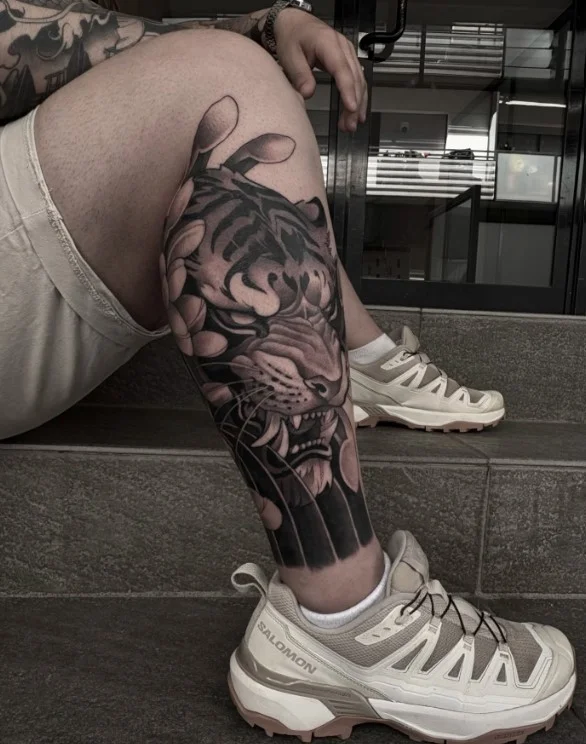 Wraparound blackwork tattoo flowing around a woman's calf