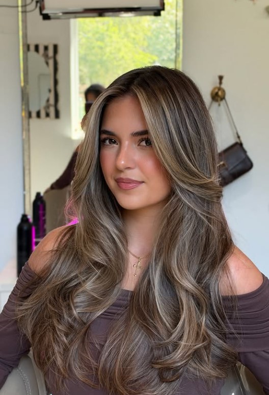 Beige blonde hair with softly blended dark roots.