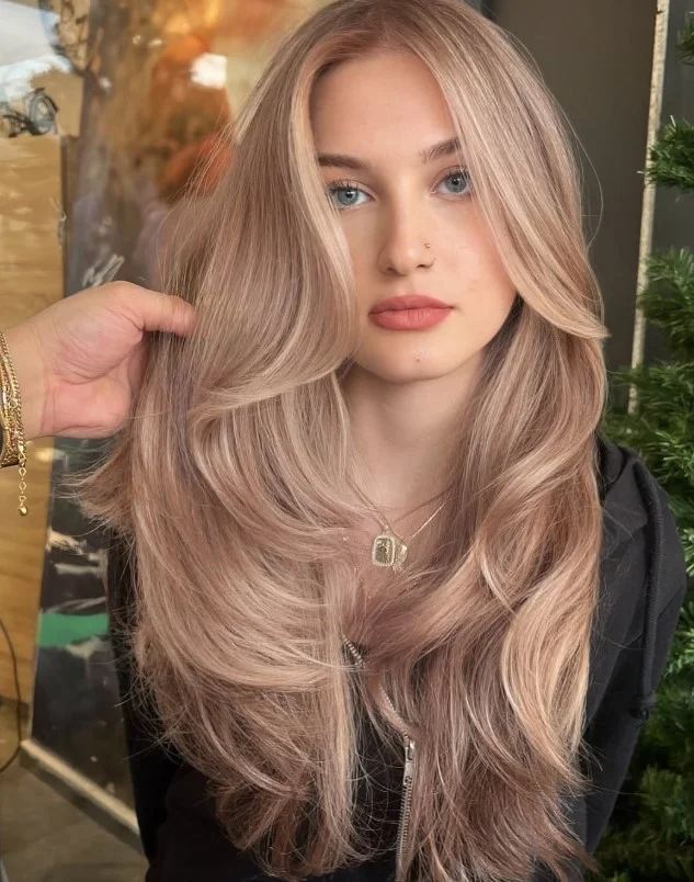 Woman with beige blonde hair featuring soft neutral tones between golden and ash blonde for a balanced, natural-looking color.