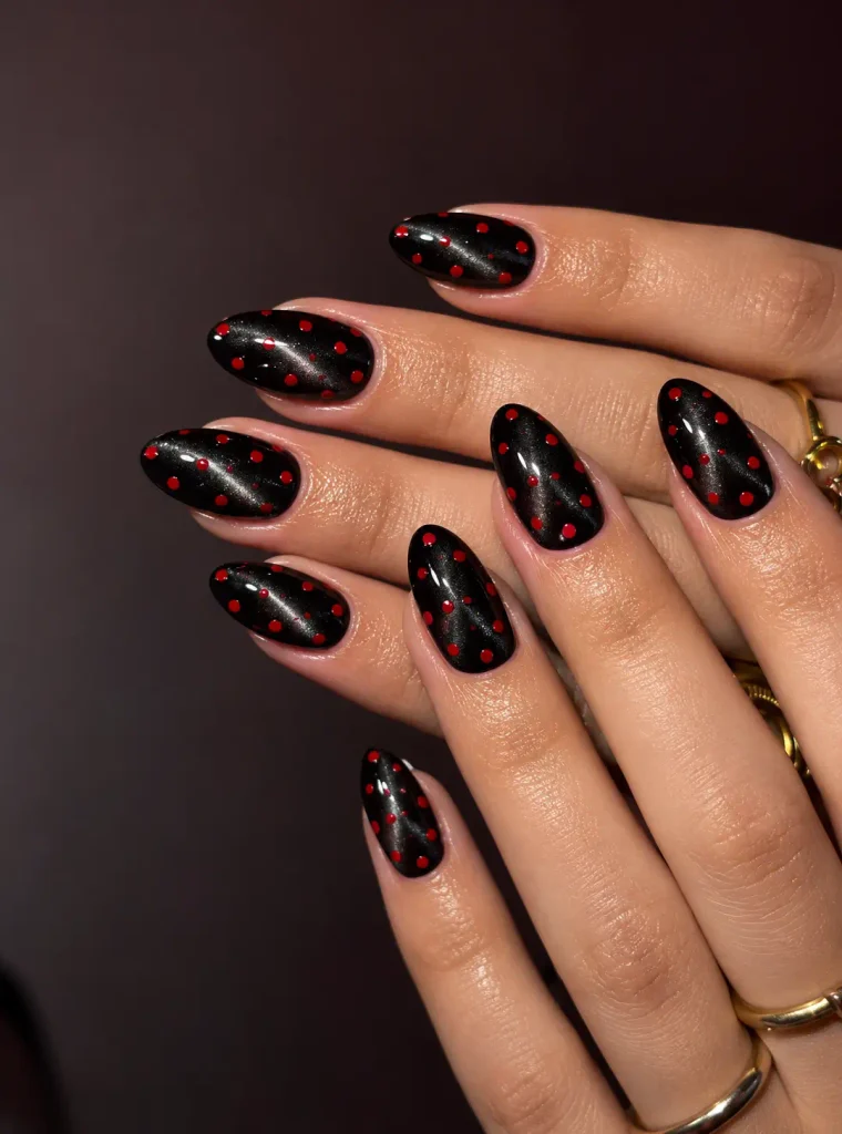 Black cat-eye nails with bright red polka dots over a magnetic shimmer finish