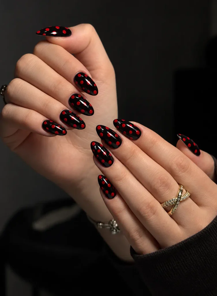 Glossy black nails with evenly spaced bright red polka dots in a classic retro design