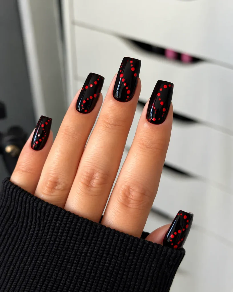 Black nails with red dots arranged in curved swirl patterns