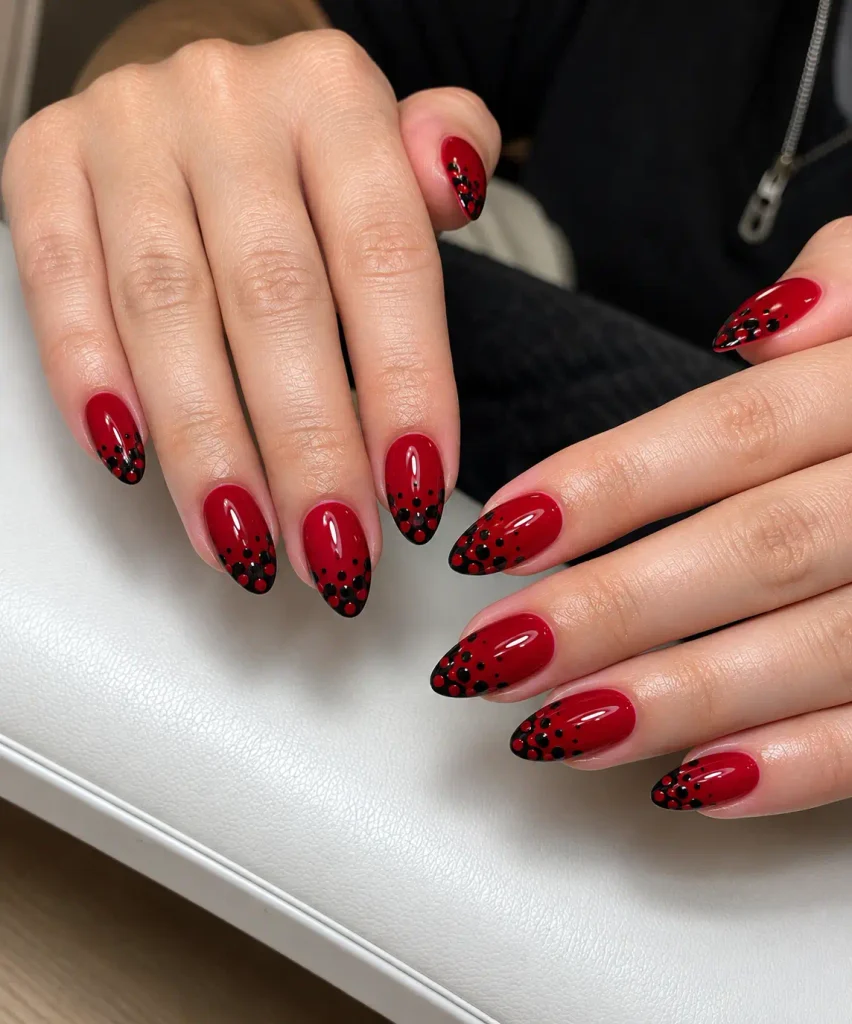 Black nails with red polka dots clustered near the tips
