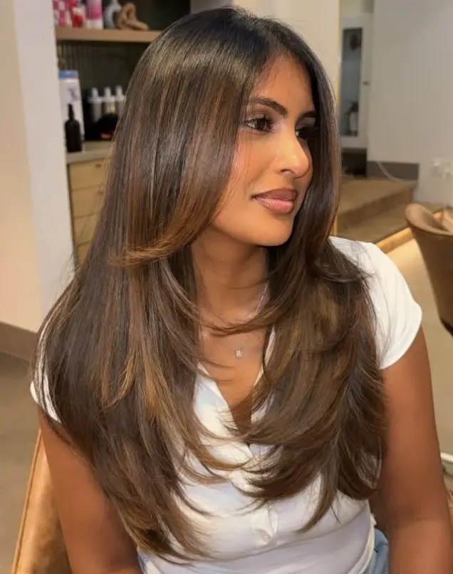 Caramel balayage highlights blended through dark brown hair on brown skin