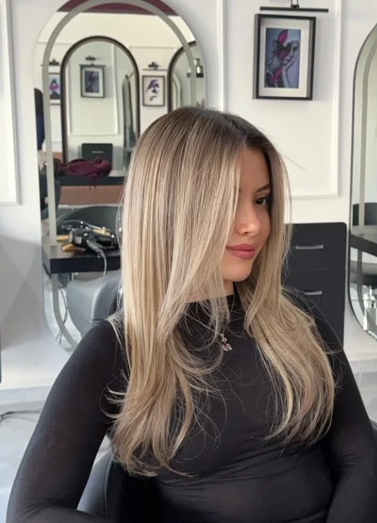 Champagne blonde hair with a shadow root for light olive skin, featuring neutral beige-blonde lengths and darker roots.