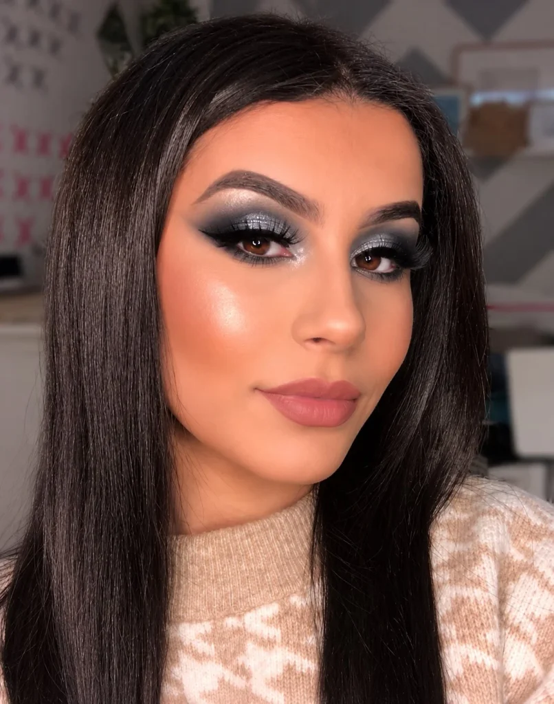 Blue eyes with charcoal eyeshadow creating a soft smoky effect around the outer corners and a subtle silver highlight at the center of the lids.