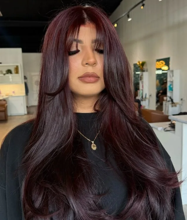 Dark cherry cola hair with a brown base and cherry-red reflections in loose waves.
