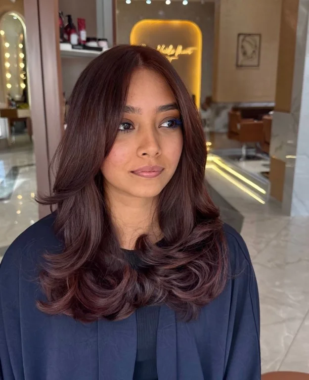 Woman with cherry cola hair combining a deep brunette base with subtle dark cherry red tones