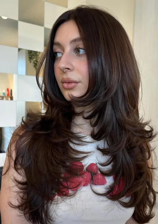Woman with glossy chocolate brown hair styled in soft waves, showing a rich brunette hair color against a fair complexion.