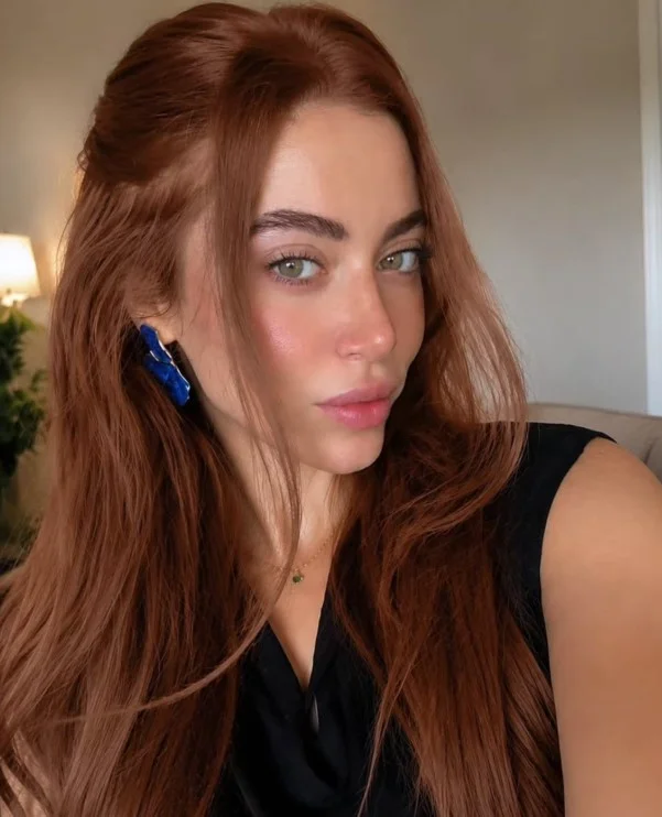 Woman with cinnamon brown hair featuring warm coppery-red reflections and dimensional brown tones.