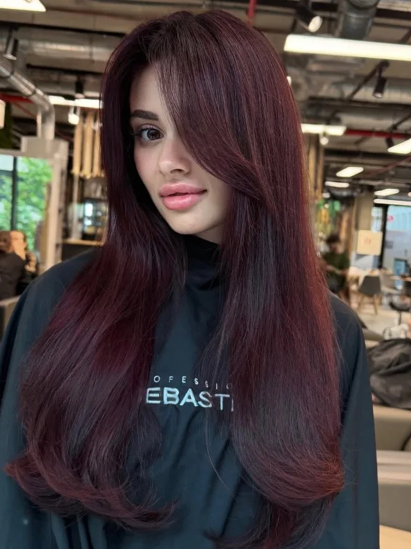 Deep burgundy brown hair with cool wine-red tones and soft waves.