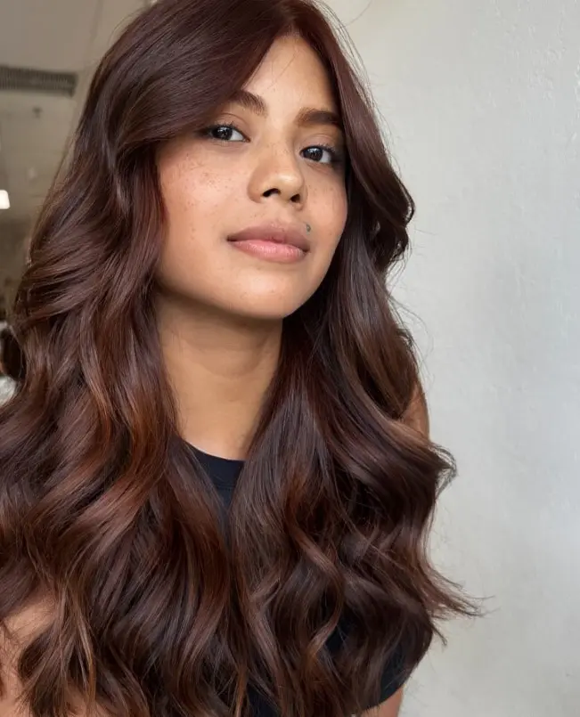 Copper highlights adding warm red-orange tones to dark brown hair