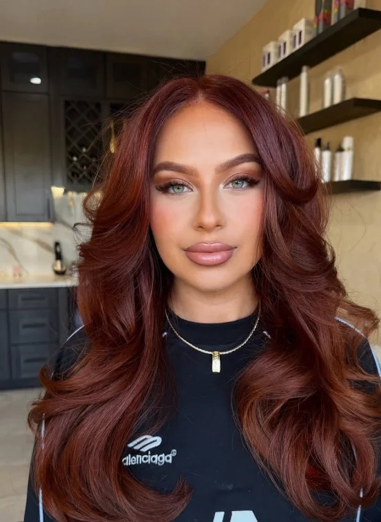 Woman with long copper red hair, warm orange-red tones, and pale skin, showcasing a vibrant hair color that complements green eyes.