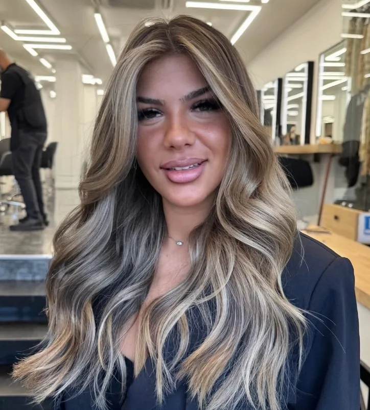 Woman with creamy beige blonde hair transitioning from a darker shadow root into soft blonde lengths