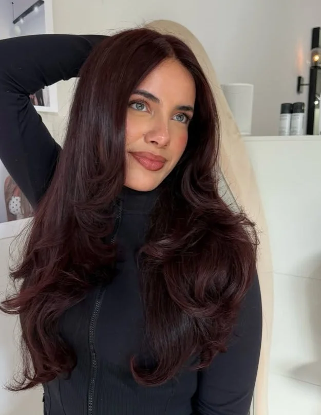 Woman with dark cherry hair featuring deep red and red-violet tones for a glossy, dramatic hair color.