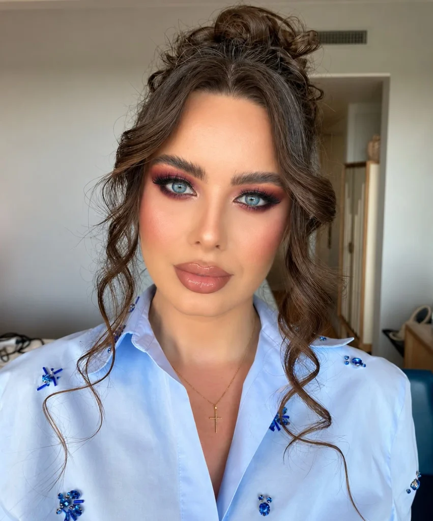 Blue eyes featuring rich berry eyeshadow concentrated on the outer lids and softly blended with warm brown for a dramatic look.