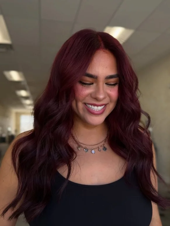 Woman with deep burgundy hair featuring rich wine red tones that show through the dark base