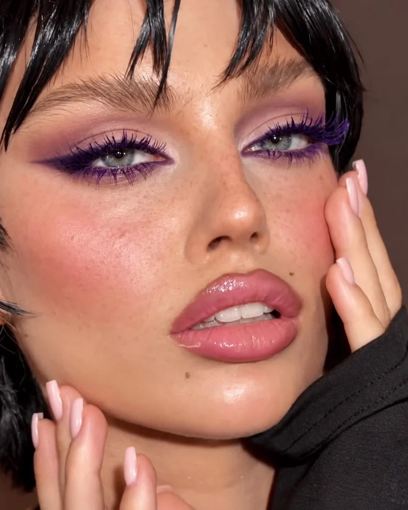 Woman with blue eyes wearing deep violet mascara for a rich purple lash look