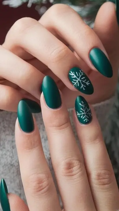 Deep emerald green Christmas nails decorated with delicate white snowflakes made from fine lines and tiny dots