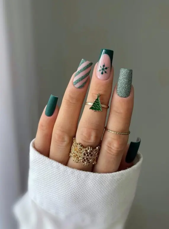 Emerald green Christmas nails with silver glitter accents and a soft pink accent nail featuring a small green holiday motif