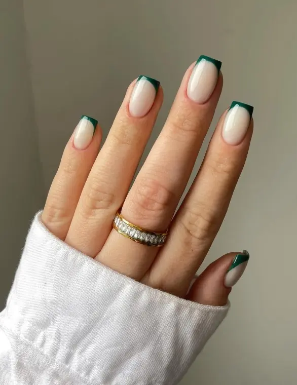 Emerald green French tip Christmas nails with deep green tips over a sheer nude or milky base