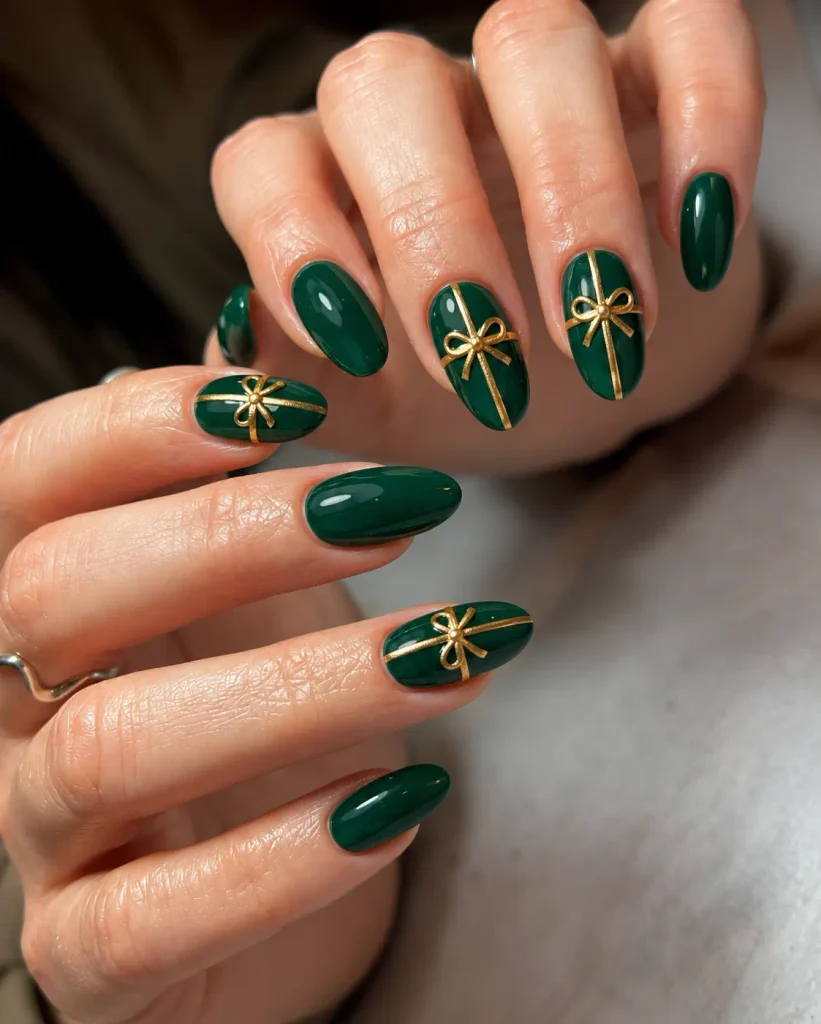 Emerald green Christmas nails decorated with fine gold gift-wrap ribbons and small bows