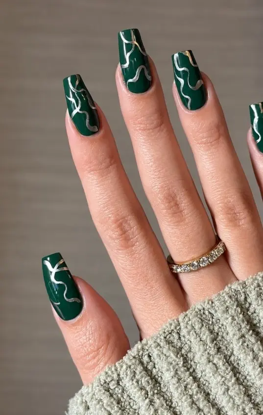 Emerald green Christmas nails decorated with delicate silver metallic swirl designs