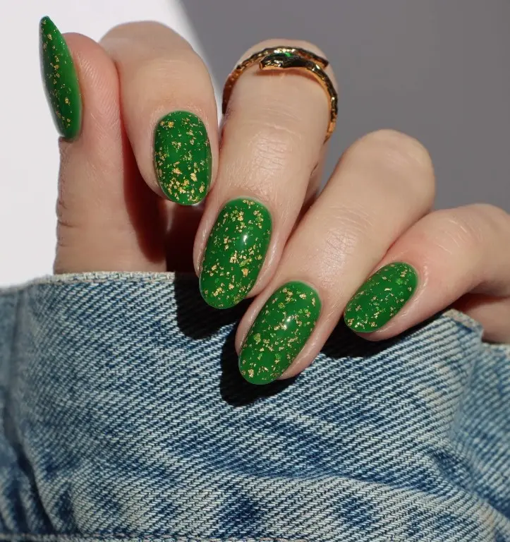 Translucent emerald green jelly nails with irregular gold foil flakes creating a glass-like Christmas manicure