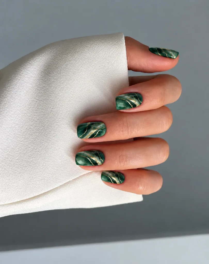 Emerald green marble Christmas nails with lighter green or milky swirls and fine gold veins