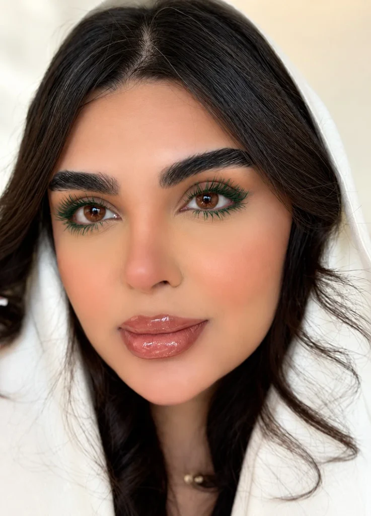 Woman with brown eyes wearing deep forest green mascara with neutral eye makeup