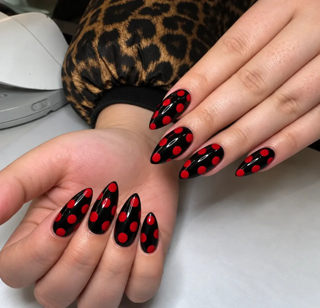 Glossy black nails with oversized cherry-red polka dots in a bold retro pattern