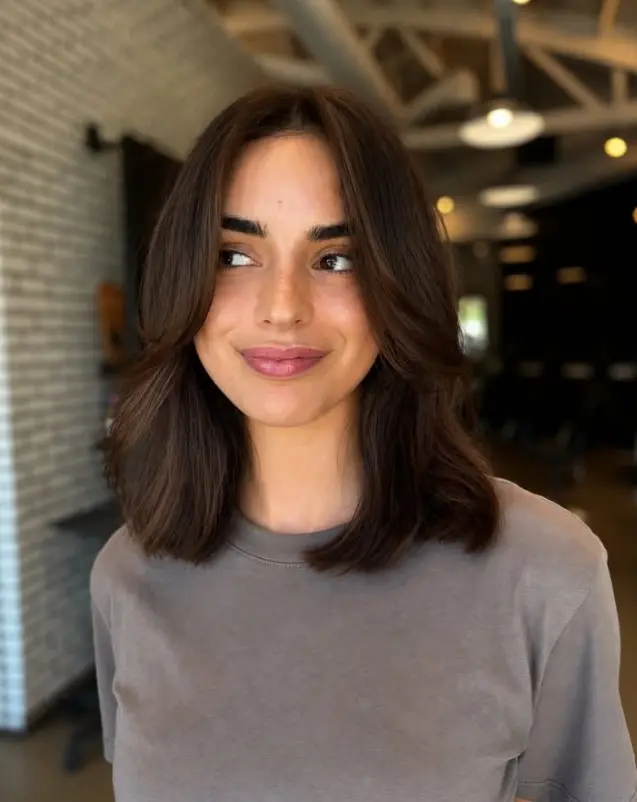 Woman with glossy dark brown shoulder-length blunt lob and smooth, straight ends