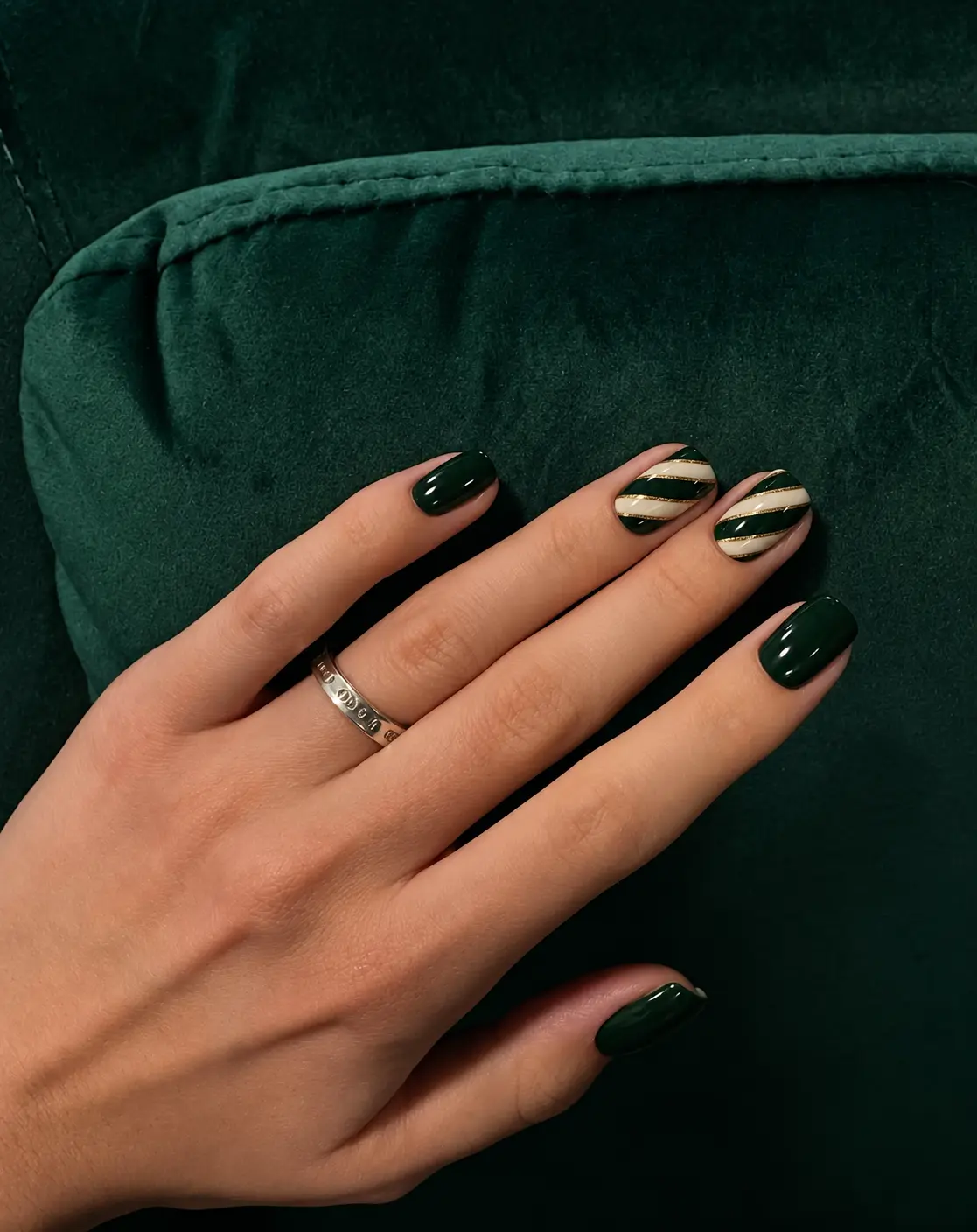 Green and cream candy cane Christmas nails with alternating stripes and fine gold accent lines