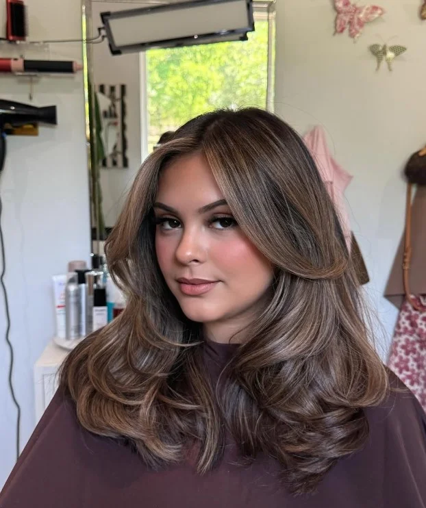 Honey blonde face-framing highlights on light olive skin with blended golden strands around the face and a brunette base.