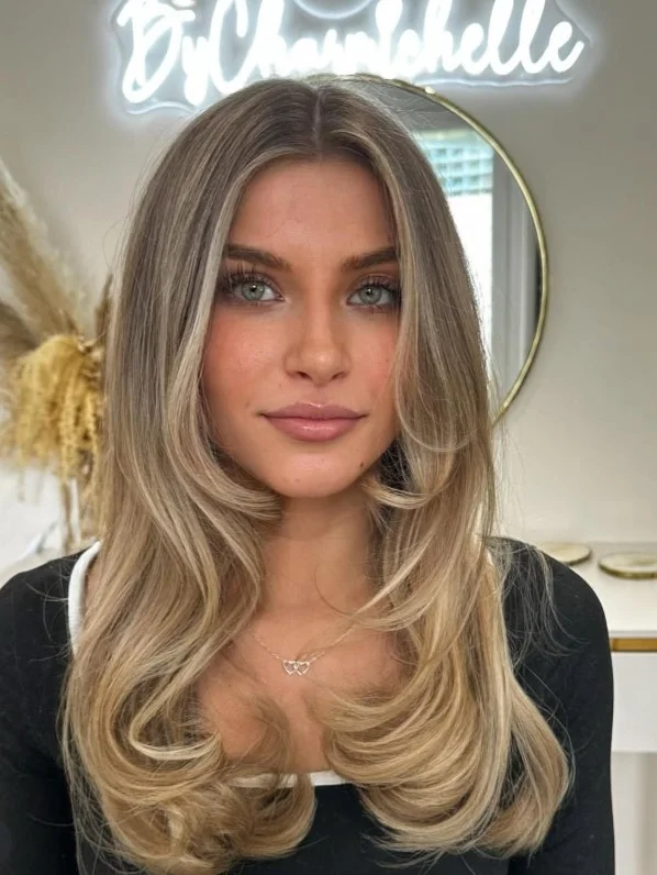 Woman with honey blonde hair featuring warm golden tones and subtle dimension for a sunlit, luminous hairstyle.