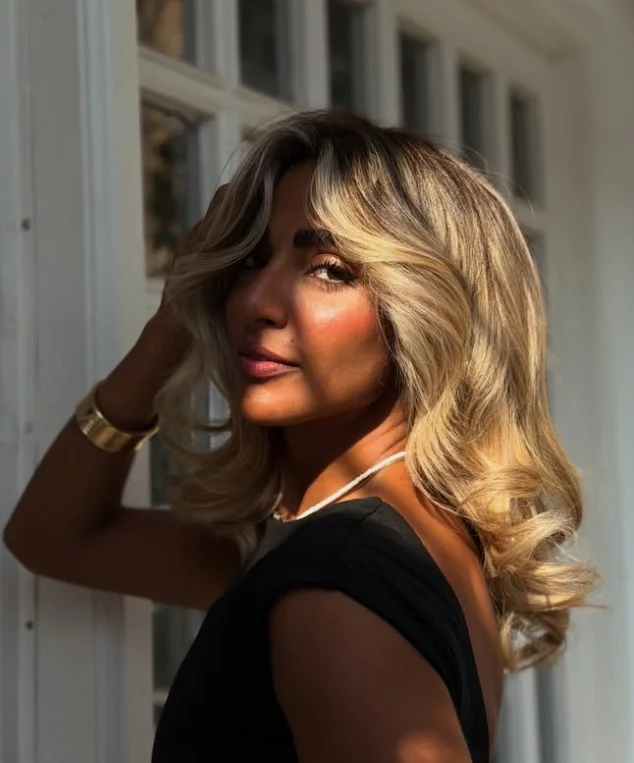 Woman with dark brunette hair and soft honey blonde highlights framing the face