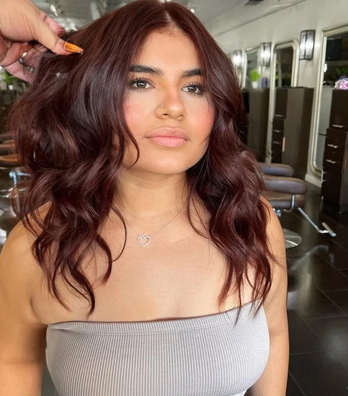 Woman with glossy mahogany brown hair featuring deep red undertones that add richness and dimension to the brunette shade.