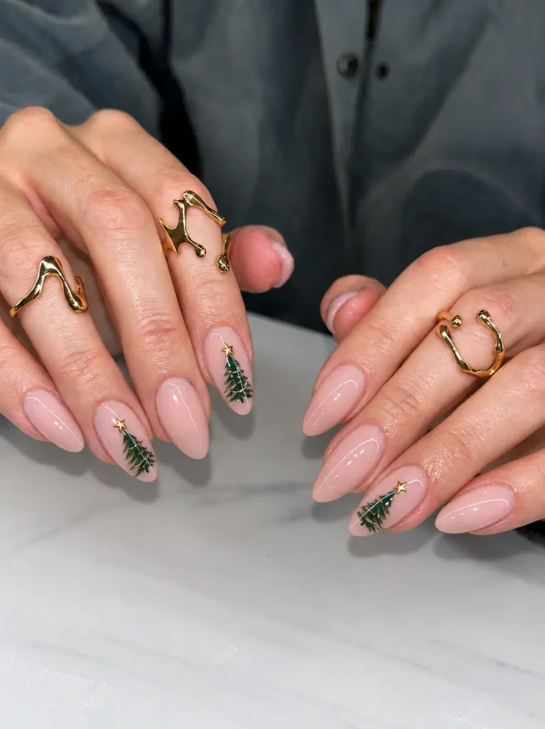 Miniature dark green Christmas tree nail art with tiny gold star toppers on a nude, milky white, or pale green base