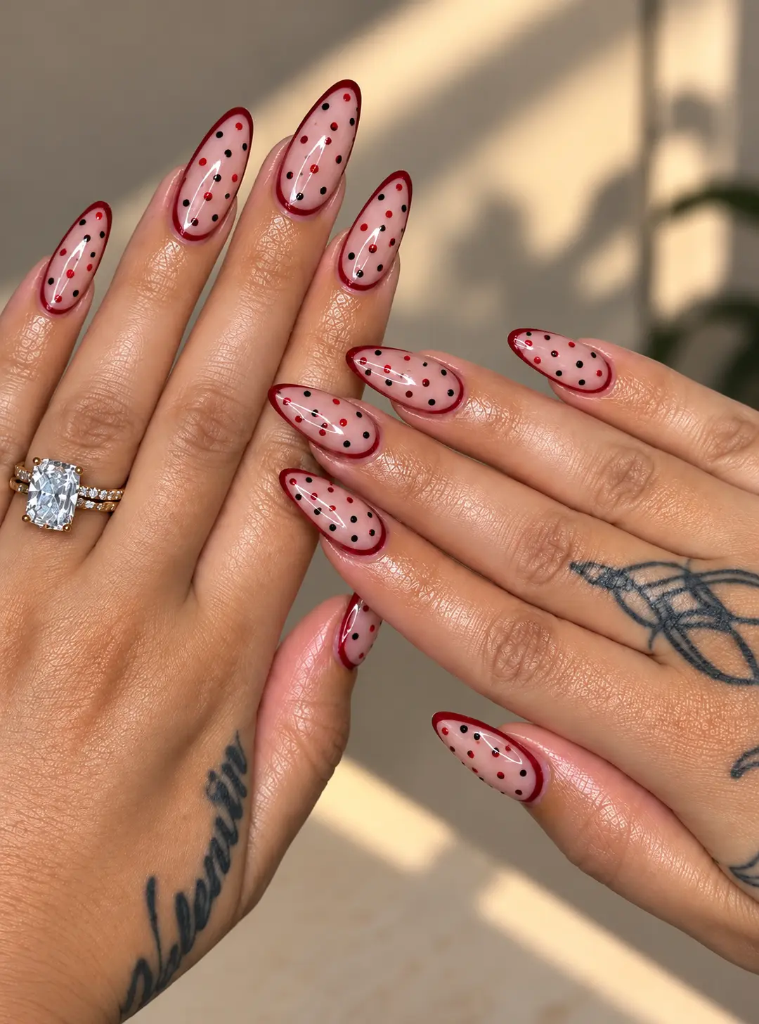 Negative-space nail art with red and black dots on a clear base