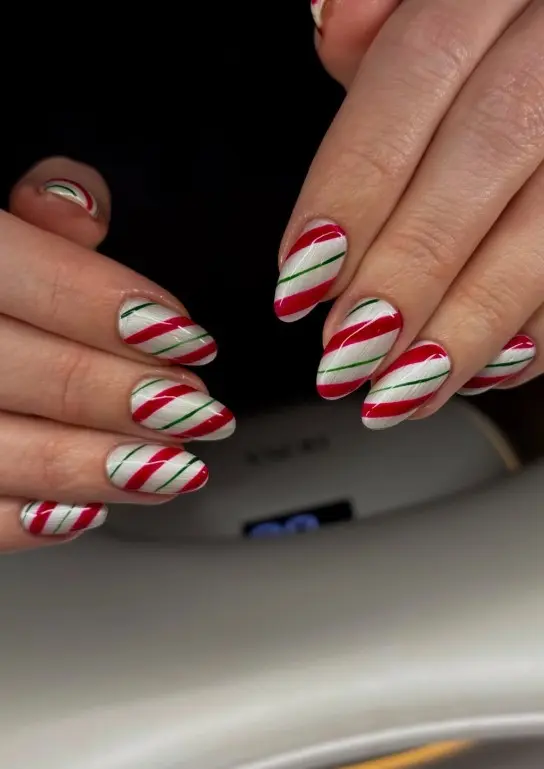 Red and green candy cane Christmas nails with diagonal red and white stripes and thin green lines