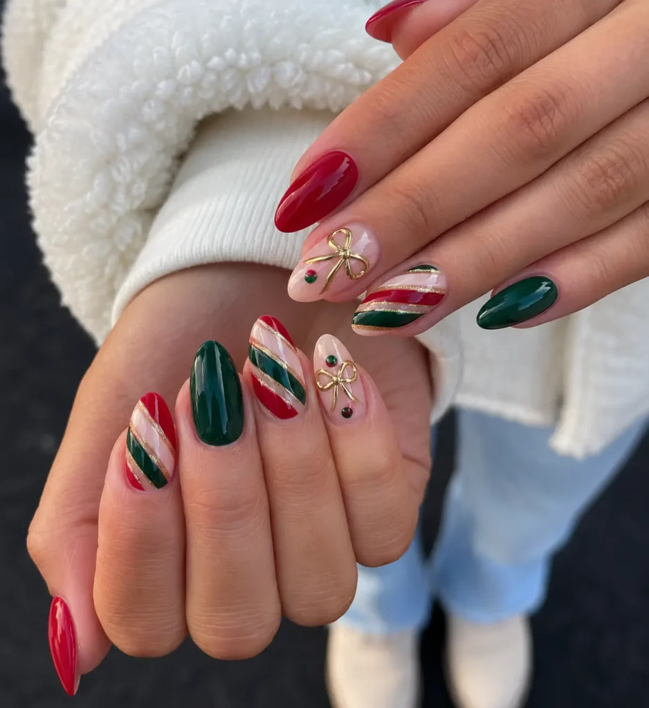 Red and green Christmas nails with delicate gold bow accents on glossy polish