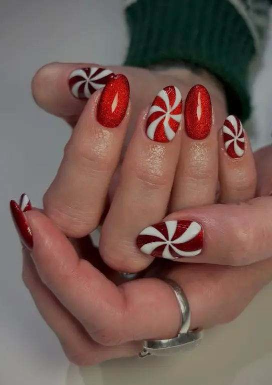 Short red and white Christmas nails featuring diagonal candy cane stripes on accent nails.