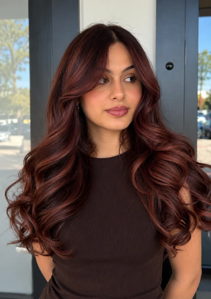 Red-brown balayage blended through dark hair with deeper roots.