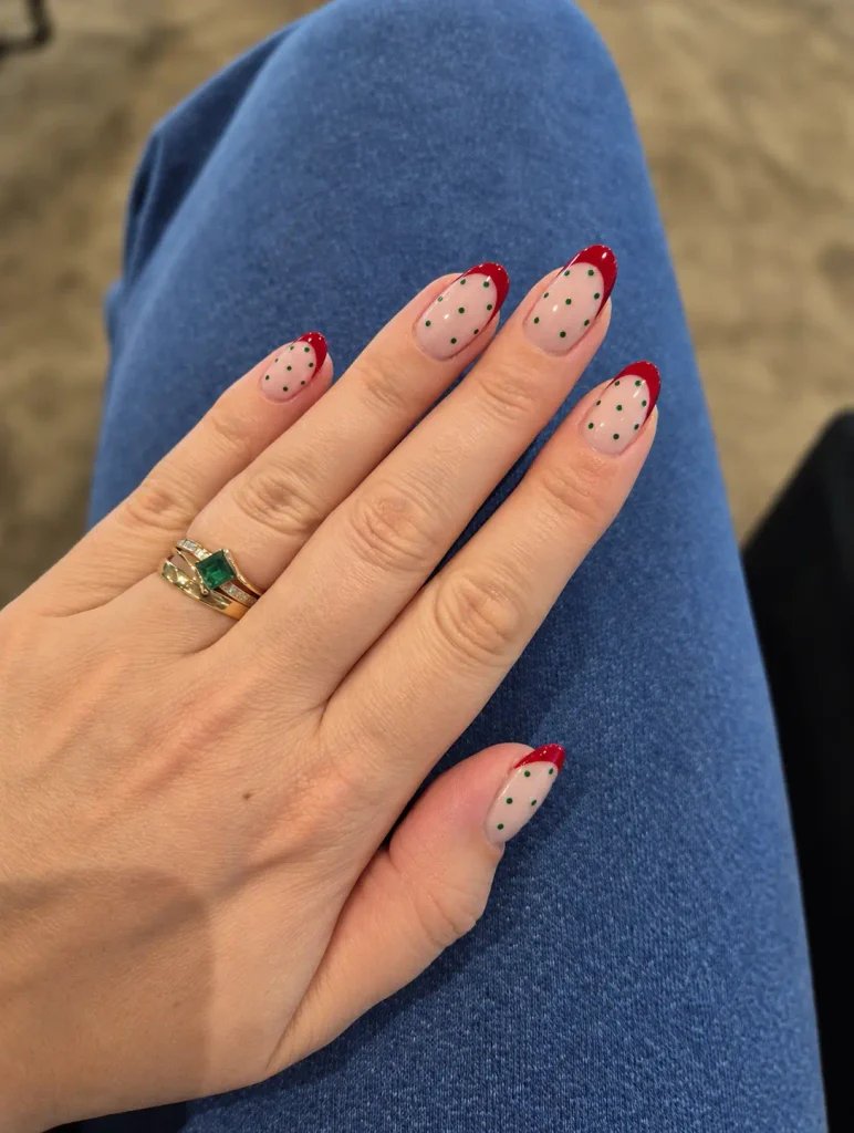 Red French tip nails with tiny green dots on a nude base