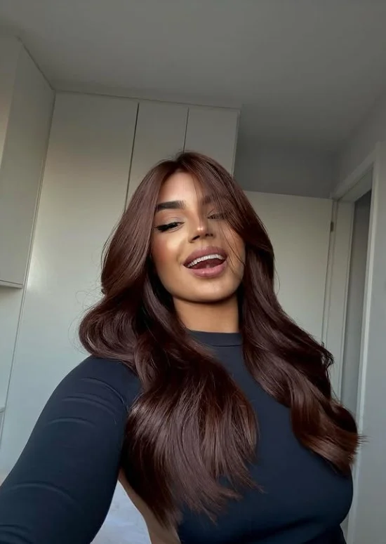 Woman with long wavy rich chocolate brown hair styled with a glossy finish for morena skin
