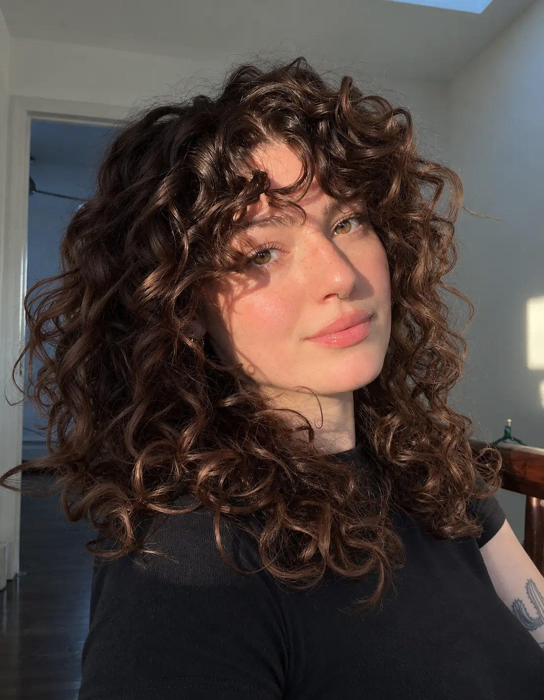 Natural dark brown shoulder-length curls shaped into a rounded layered cut