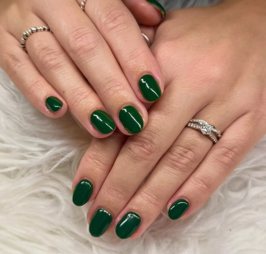 Short glossy emerald green nails with a smooth, rich green polish and a simple festive finish