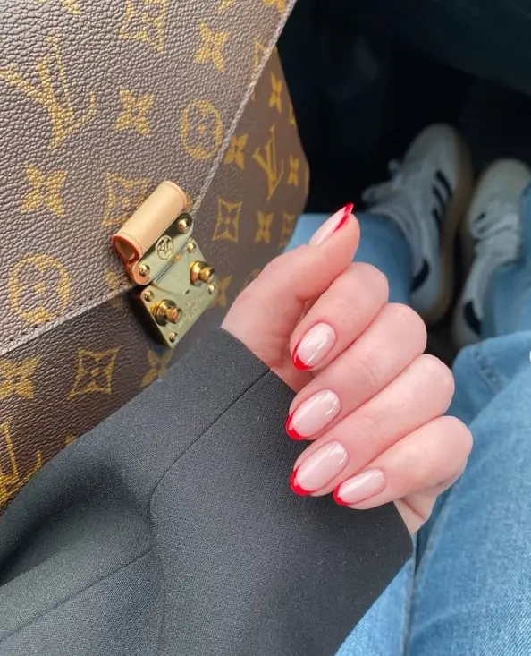 Short red French tip Christmas nails with thin cherry red tips over a sheer pink base.